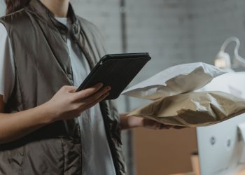 A person using a tablet to manage packages in an indoor setting, highlighting technology and logistics.