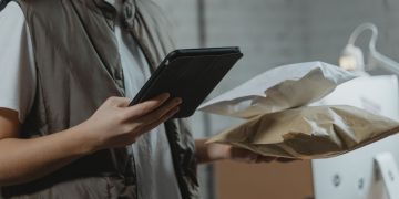 A person using a tablet to manage packages in an indoor setting, highlighting technology and logistics.