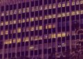 Illuminated urban office building facade at night in New Delhi, showcasing modern architecture with glowing windows.