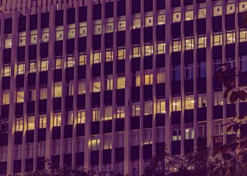 Illuminated urban office building facade at night in New Delhi, showcasing modern architecture with glowing windows.