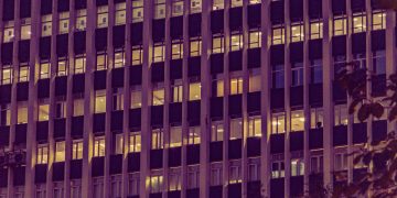 Illuminated urban office building facade at night in New Delhi, showcasing modern architecture with glowing windows.