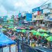 A bustling market with colorful umbrellas and billboards in Lagos, Nigeria.