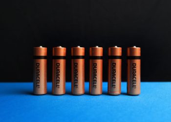 A lined up set of AA batteries with black and blue background.