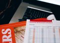 Detailed close-up of economic and financial documents on a laptop keyboard, highlighting data analytics.