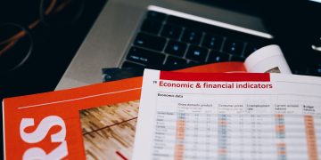 Detailed close-up of economic and financial documents on a laptop keyboard, highlighting data analytics.