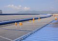 Workers installing solar panels on a large roof, highlighting renewable energy and sustainability.