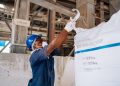Industrial worker checking a large soda ash bag in a manufacturing facility.