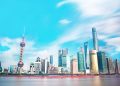 Stunning view of Shanghai skyline with the iconic Oriental Pearl Tower and modern skyscrapers under a bright blue sky.