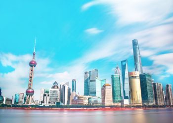 Stunning view of Shanghai skyline with the iconic Oriental Pearl Tower and modern skyscrapers under a bright blue sky.