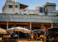 A vibrant urban street market scene with auto rickshaws and local shops.