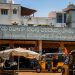 A vibrant urban street market scene with auto rickshaws and local shops.