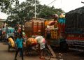 Men loading colorful cargo trucks on a bustling Kolkata street.