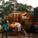 Men loading colorful cargo trucks on a bustling Kolkata street.