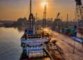 A vibrant scene of cargo operations during sunrise at a busy port in Indonesia.