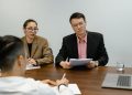 Colleagues engaged in a business meeting, discussing documents in an office setting.