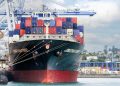 A large cargo ship with colorful containers docked at Auckland Port, New Zealand.