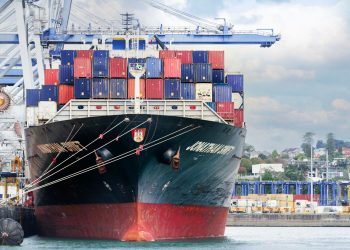 A large cargo ship with colorful containers docked at Auckland Port, New Zealand.