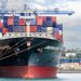 A large cargo ship with colorful containers docked at Auckland Port, New Zealand.