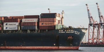 Cargo ship with containers and cranes in Hamburg port.
