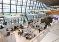 A bustling trade show exhibition inside a modern hall with people networking and exploring booths.