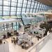 A bustling trade show exhibition inside a modern hall with people networking and exploring booths.