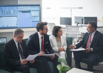 Group of business professionals discussing financial strategies in a modern office setting.