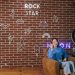 Asian woman streaming content with neon signs on a brick wall. Modern influencer setup.