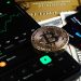 Bitcoin coin with financial data, credit cards, and currency on a desk.
