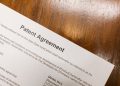 Detailed close-up of a patent agreement document on a polished wooden table.