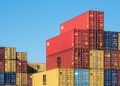 A vibrant collection of stacked shipping containers under a clear, blue sky. Ideal for logistic themes.
