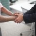 Close-up of a formal handshake between two businessmen in an office environment.