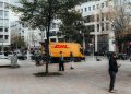 A busy city square in Berlin featuring a DHL truck and pedestrians enjoying an urban environment.