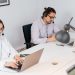 Two office workers focusing on tasks at a call center, using laptops and headsets.