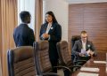 Three professionals discussing business strategy in a modern conference room.