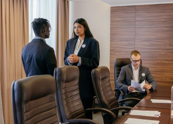 Three professionals discussing business strategy in a modern conference room.
