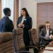 Three professionals discussing business strategy in a modern conference room.