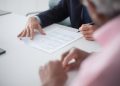 Two professionals engaging in a business meeting, signing documents for a consulting agreement.