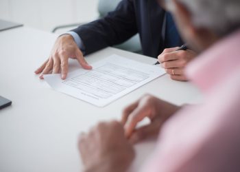 Two professionals engaging in a business meeting, signing documents for a consulting agreement.