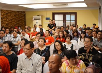 A diverse group of adults attending a conference in an Indonesian indoor setting.