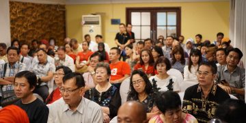 A diverse group of adults attending a conference in an Indonesian indoor setting.