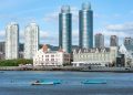 A stunning cityscape featuring modern high-rise buildings with a waterfront view and small boats.