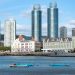 A stunning cityscape featuring modern high-rise buildings with a waterfront view and small boats.