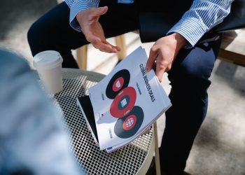 A businessman discusses global business deals with visual aids during an outdoor meeting.