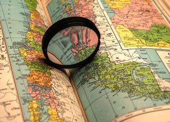 A close-up of a colorful world map with a magnifying glass highlighting details.