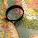 A close-up of a colorful world map with a magnifying glass highlighting details.