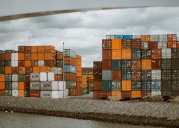 Colorful shipping containers stacked in Rotterdam harbor, under overcast skies.