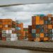 Colorful shipping containers stacked in Rotterdam harbor, under overcast skies.