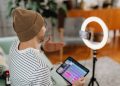 Adult male recording podcast using tablet and cellphone with ring light indoors