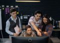 Group of professionals discussing a project at a computer in a modern office environment.