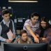 Group of professionals discussing a project at a computer in a modern office environment.